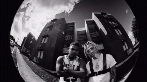 A Black And White Photo Of Two Men Standing In Front Of A Building With One Wearing A Number 25 Jersey GIF