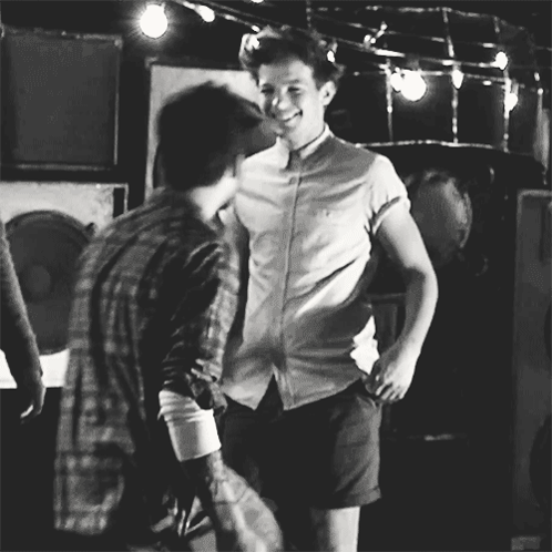 A Black And White Photo Of Two Men Standing Next To Each Other And Smiling . GIF