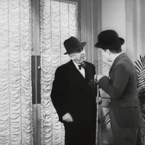 A Black And White Photo Of Two Men Talking GIF