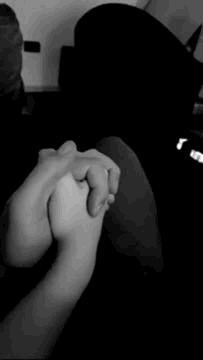 A Black And White Photo Of Two People Holding Hands . GIF