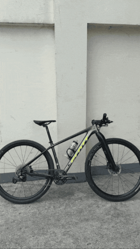 A Black And Yellow Bicycle Is Parked In Front Of A Wall GIF