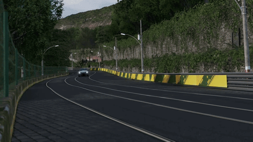 A Black Car Is Driving Down A Road Next To A Wall GIF