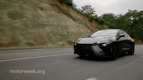 A Black Car Is Driving Down A Road With Motorweek.org In The Corner GIF