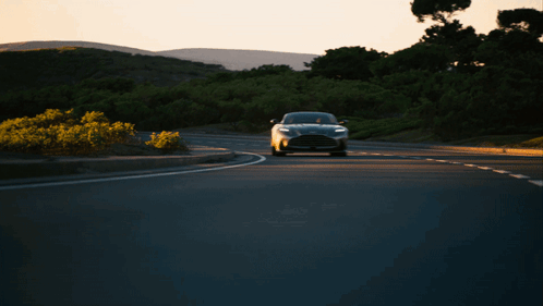A Black Car Is Driving Down A Road With Trees In The Background GIF