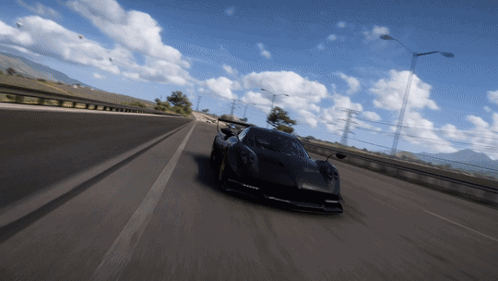 A Black Car Is Driving On A Highway With Mountains In The Background GIF