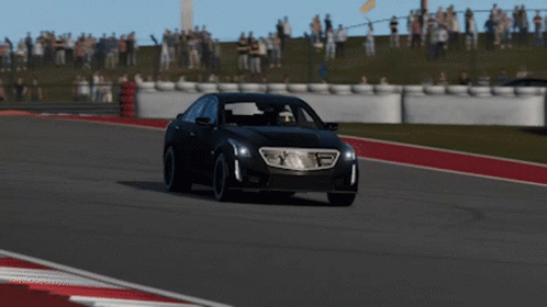 A Black Car Is Driving On A Race Track With A Crowd In The Background GIF