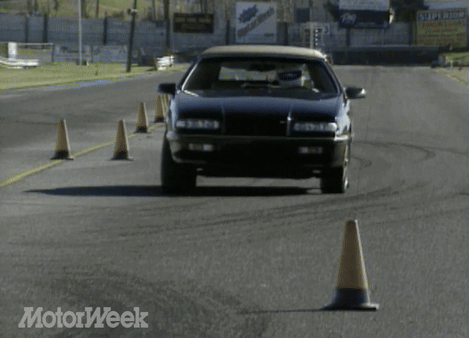 A Black Car Is Driving On A Road With A Motorweek Logo In The Corner GIF