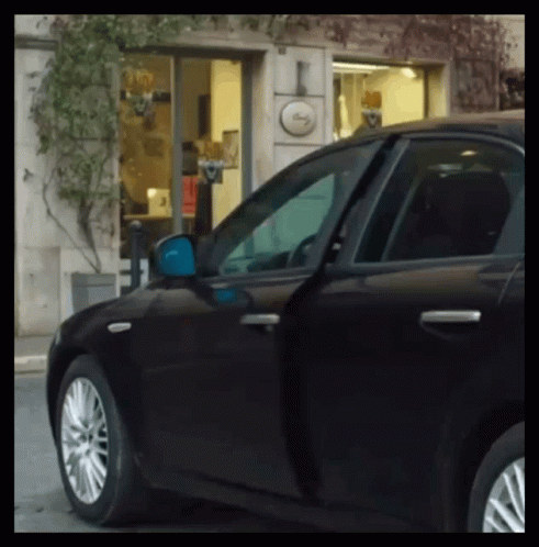 A Black Car Is Parked In Front Of A Building With A Sign That Says ' I ' On It GIF