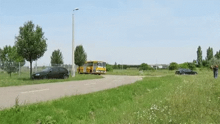 A Black Car Is Parked On The Side Of The Road Next To A Bus GIF