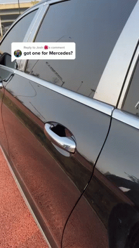 A Black Car Is Parked On The Side Of The Road Next To A Post That Says " Got One For Mercedes " GIF