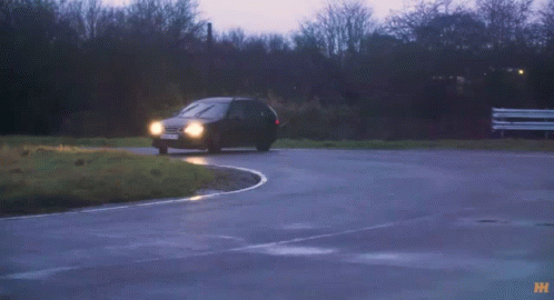 A Black Car With A License Plate That Says Lkd70 Is Driving Down A Wet Road GIF