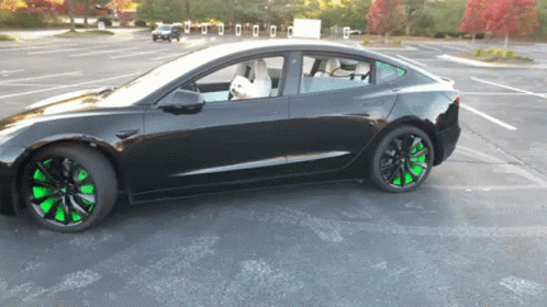 A Black Car With Green Wheels Is Parked In A Lot GIF
