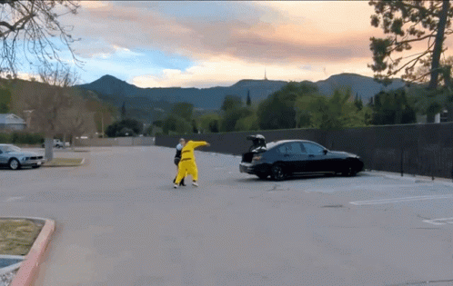 A Black Car With The Trunk Open Is Parked In A Parking Lot With Mountains In The Background GIF
