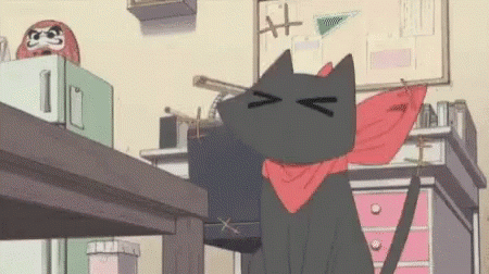 A Black Cat Wearing A Red Scarf Around Its Neck Is Sitting On A Desk . GIF