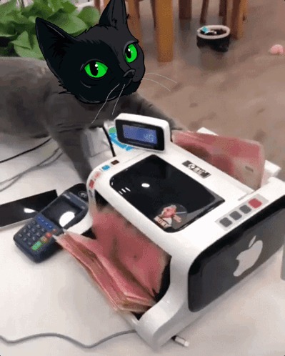 A Black Cat With Green Eyes Sits Next To A Machine That Has An Apple Logo GIF