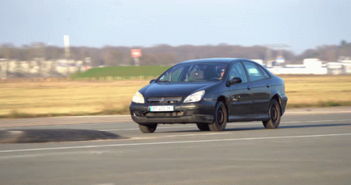 A Black Citroen Car With A License Plate That Says Tc - Nc - Nk Is Driving Down A Road GIF