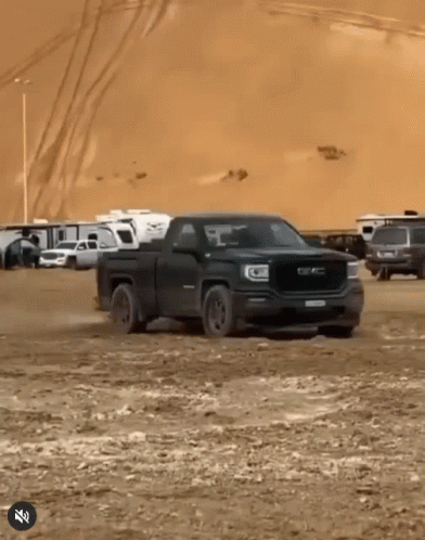 A Black Gmc Truck Is Driving Through The Dirt GIF