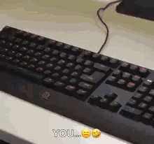 A Black Keyboard Is Sitting On A White Table And Says You On The Bottom GIF