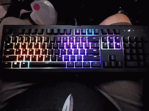 A Black Keyboard With Rainbow Colored Keys Is Sitting On A Persons Lap GIF