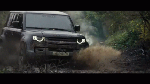 A Black Land Rover Defender Is Driving Through A Muddy Area GIF