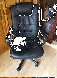 a black leather office chair is on a wooden floor