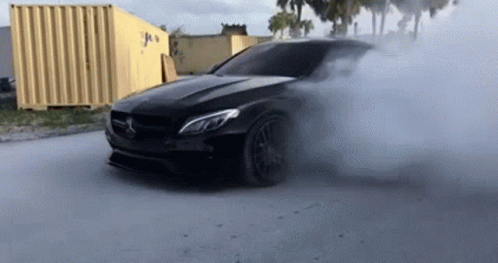 A Black Mercedes Benz Is Doing A Burnout On A Road . GIF