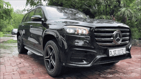 A Black Mercedes Is Parked On A Brick Driveway With A Namaste Car Logo In The Background GIF