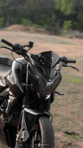 A Black Motorcycle Is Parked In A Field GIF