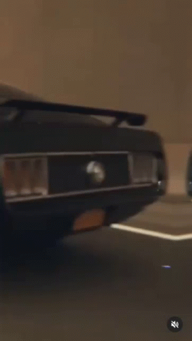 a black mustang is driving down a highway at sunset .