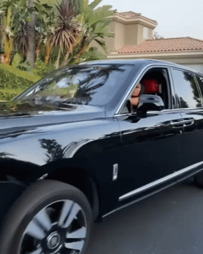 A Black Rolls Royce Is Parked In A Driveway In Front Of A House GIF