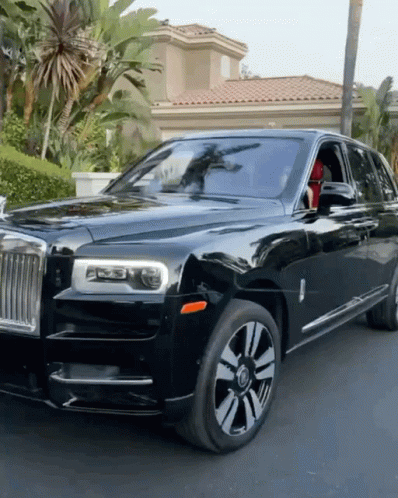 A Black Rolls Royce Is Parked In Front Of A Palm Tree GIF