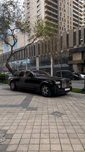 A Black Rolls Royce Is Parked On The Sidewalk In Front Of A Building GIF