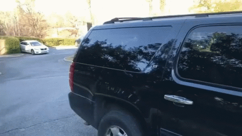 A Black Suv Is Parked In A Parking Lot With Other Cars GIF