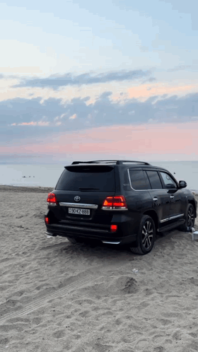 A Black Toyota Suv Is Parked On A Sandy Beach With A License Plate That Says Bscn 888 GIF