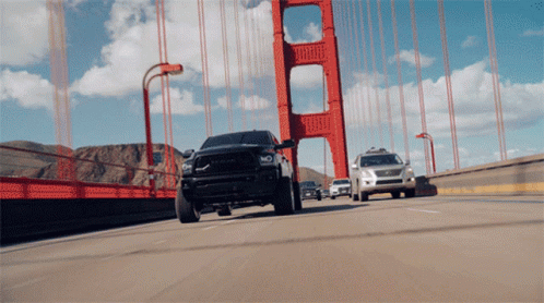 A Black Truck Is Driving Over A Bridge GIF