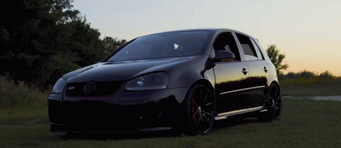 A Black Volkswagen Is Parked In The Grass GIF