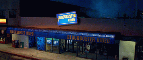 A Blockbuster Video Store At Night With A Blue Awning GIF