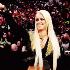 A Blonde Woman In A Black And Gold Outfit Stands In Front Of A Crowd With The Number 62 On Her Shirt GIF