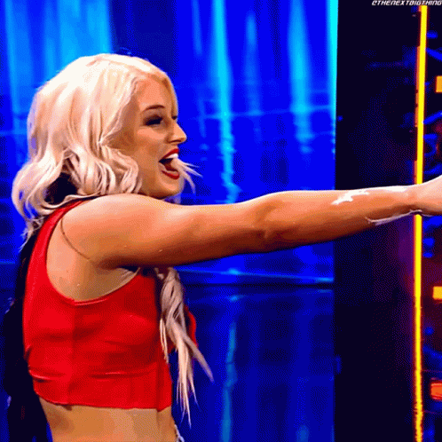 A Blonde Woman In A Red Top Is Standing In Front Of A Blue Background . GIF