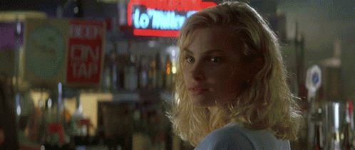 A Blonde Woman Is Smiling In Front Of A Sign That Says No Water To Tap GIF