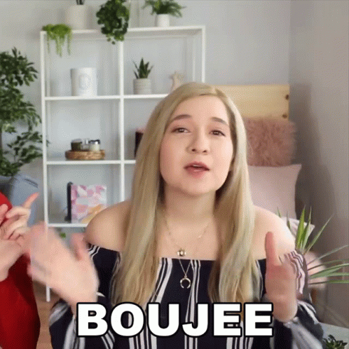A Blonde Woman Says Boujee In Front Of A Shelf GIF
