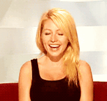 a blonde woman wearing a black tank top is laughing