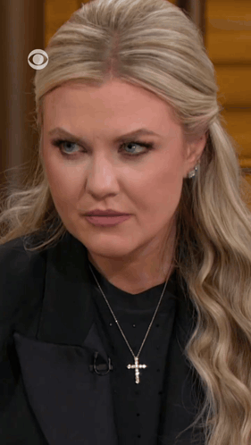 A Blonde Woman Wearing A Cross Necklace And A Black Jacket GIF