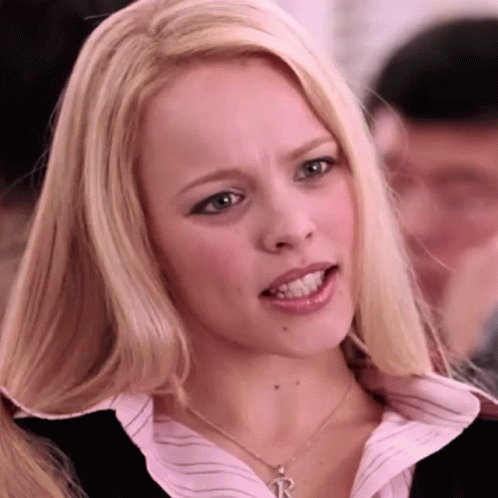 A Blonde Woman Wearing A Necklace With A Letter R On It GIF