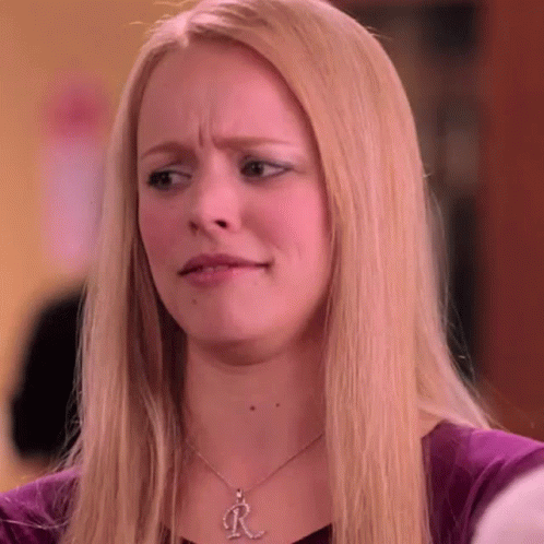 A Blonde Woman Wearing A Necklace With The Letter R On It Is Making A Funny Face . GIF