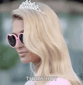 A Blonde Woman Wearing A Tiara And Sunglasses Is Standing In Front Of A Building . GIF