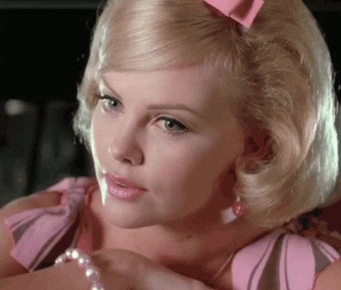 A Blonde Woman With A Pink Bow In Her Hair Is Wearing A Pearl Bracelet GIF