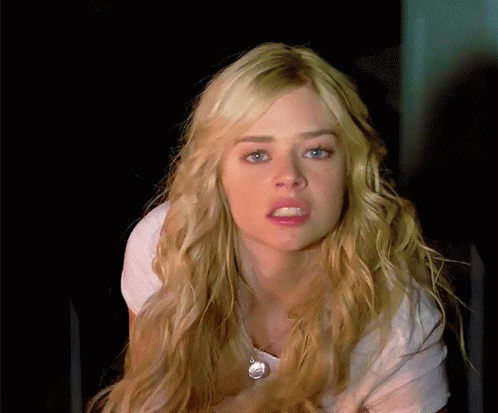 A Blonde Woman With Blue Eyes Is Wearing A White Shirt And Necklace GIF
