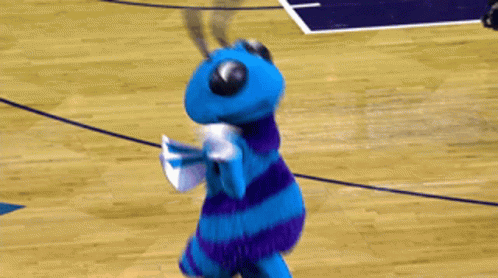 A Blue And Purple Mascot Stands On A Basketball Court GIF