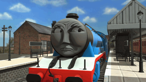 A Blue And Red Train With An Angry Face Is On The Tracks GIF